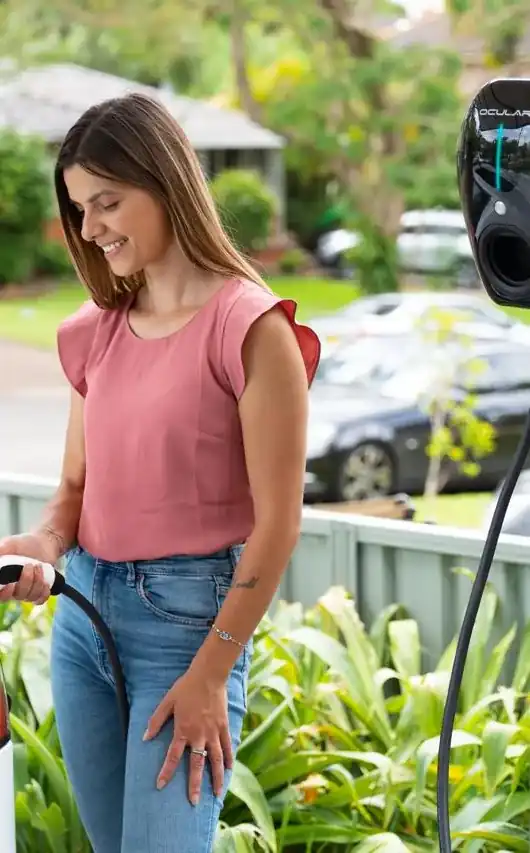 Woman plugging her electric car into an Ocular home EV charger mounted on a carport post